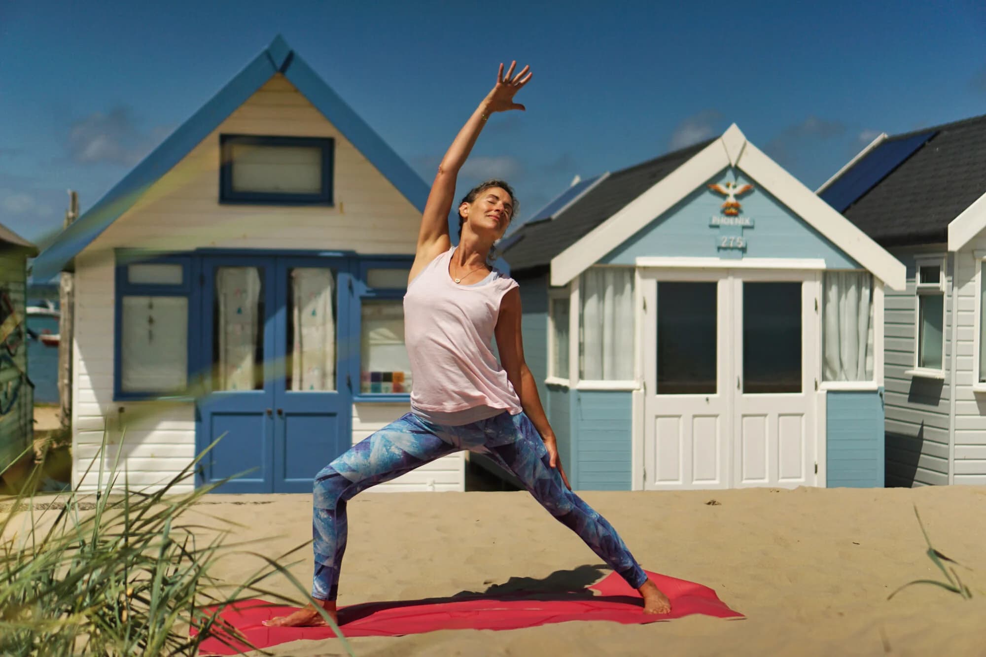 Rebekah practising yoga by the beach huts at Mudeford