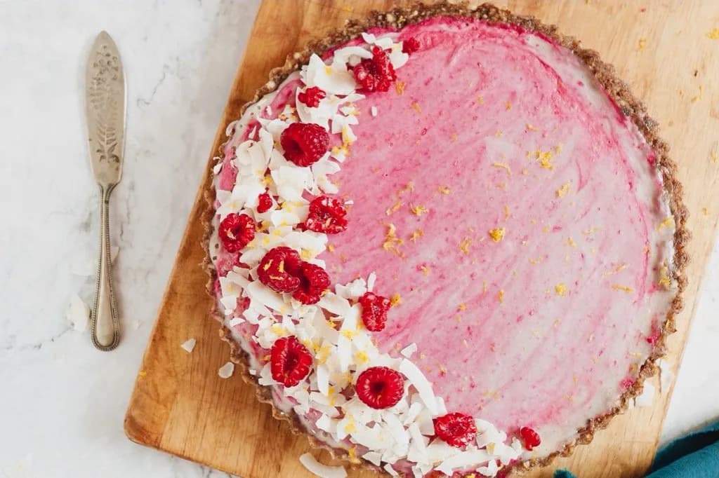Raspberry and coconut tart on a wooden serving board